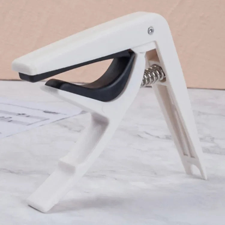 White plastic guitar capo with black rubber grip and silver spring for acoustic classic guitar and musical instrument ukulele