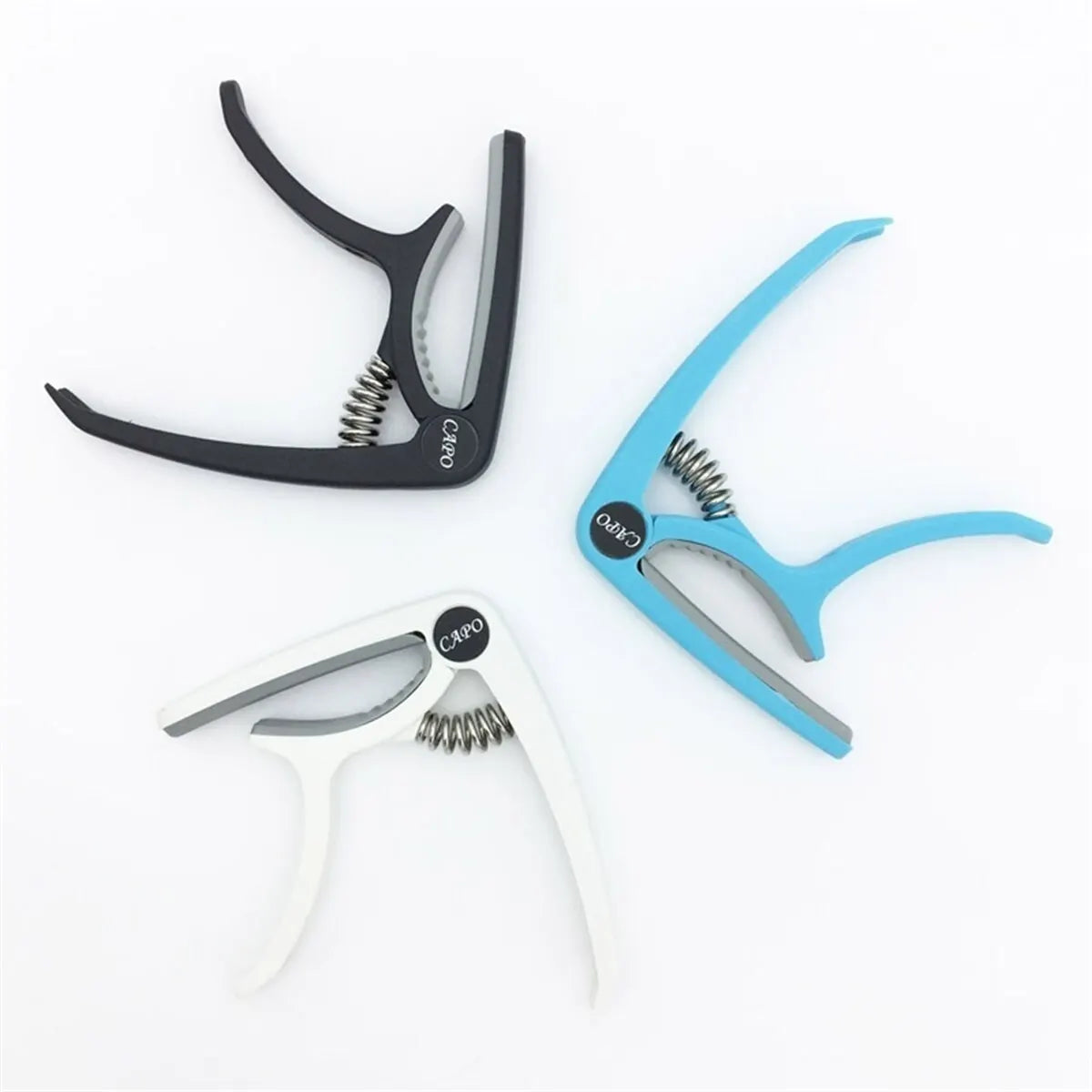 Three capo brand guitar capos in black blue and white with spring-loaded mechanism for acoustic classic guitar ukulele