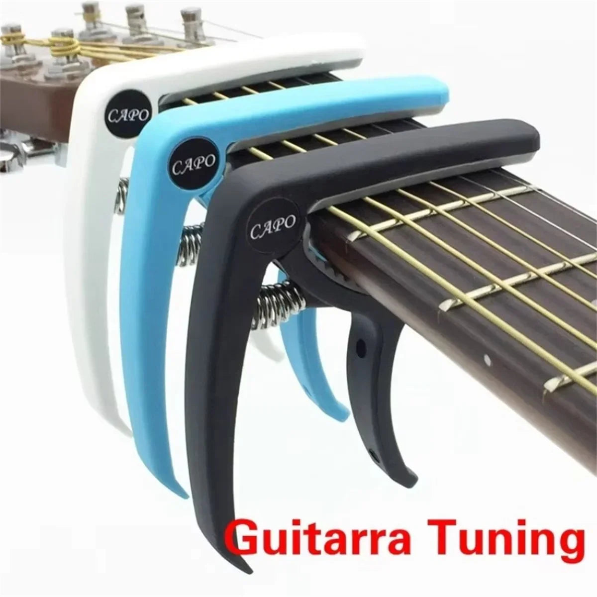 Three guitar capos in white blue and black clamped on a fretboard for acoustic classic guitar and musical instrument ukulele