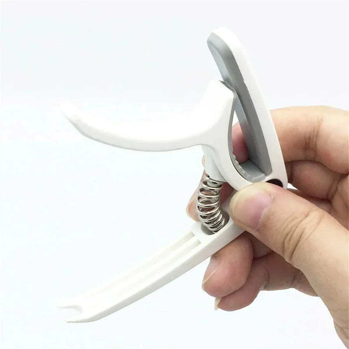White plastic guitar capo with silver metal spring and gray hinge accent for acoustic classic guitar and ukulele use