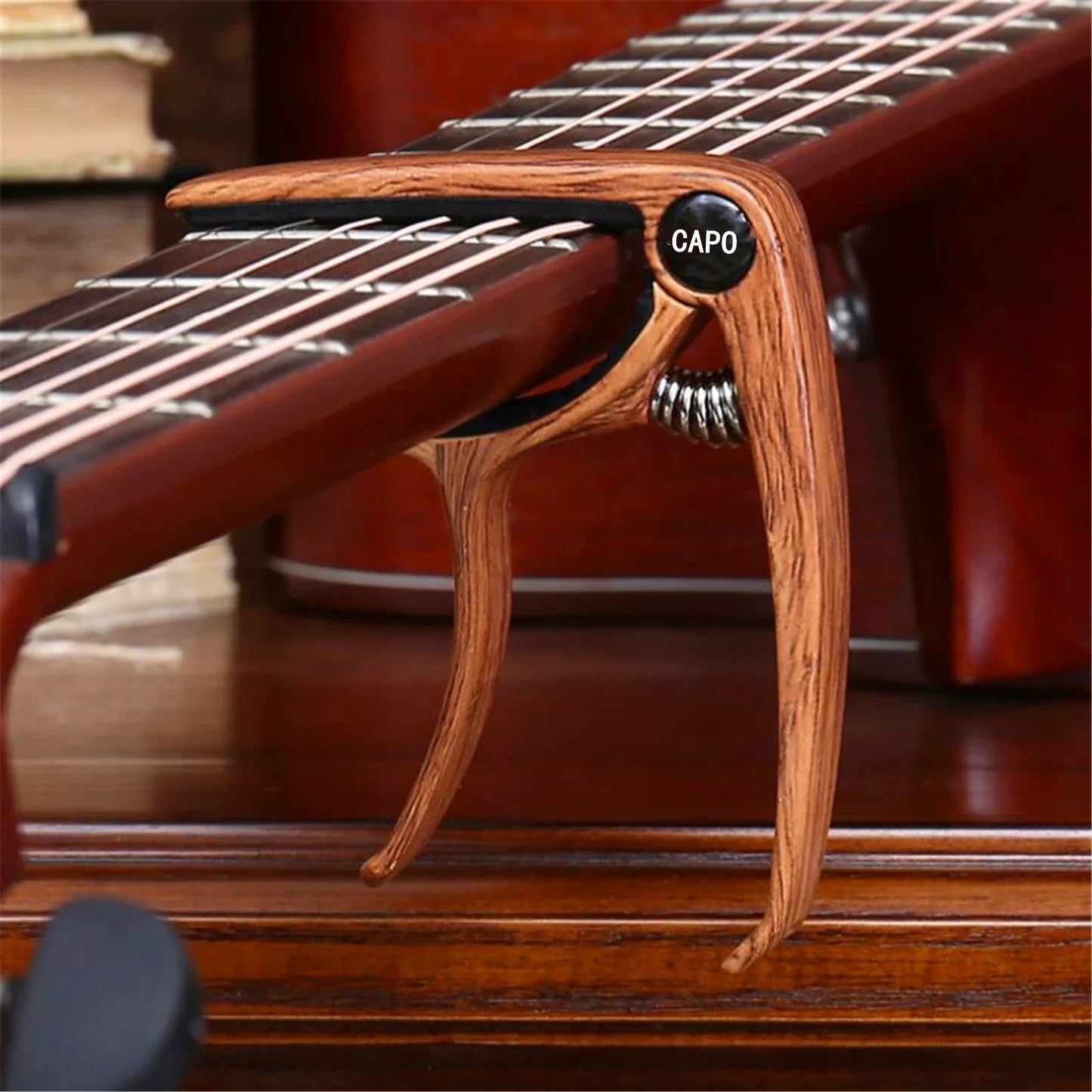 A wooden guitar capo metal with a black label and silver spring mechanism zinc alloy construction for tuning clamp