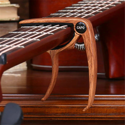 A wooden guitar capo metal with a black label and silver spring mechanism zinc alloy construction for tuning clamp