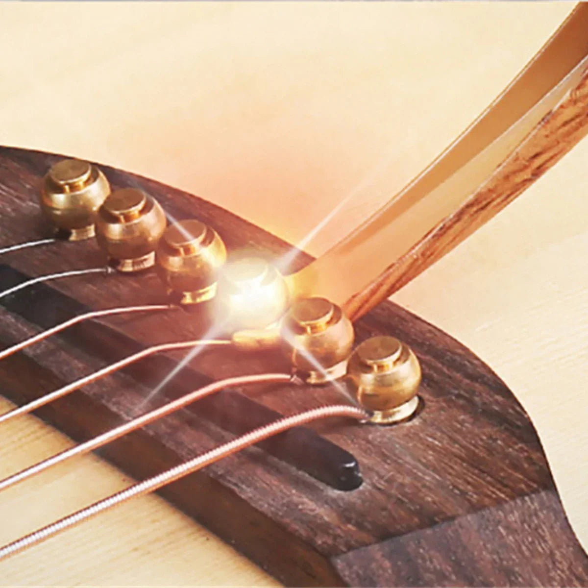 Golden tuning pegs on dark wood guitar neck with guitar capo metal made of zinc alloy construction and guitar tuner clamp