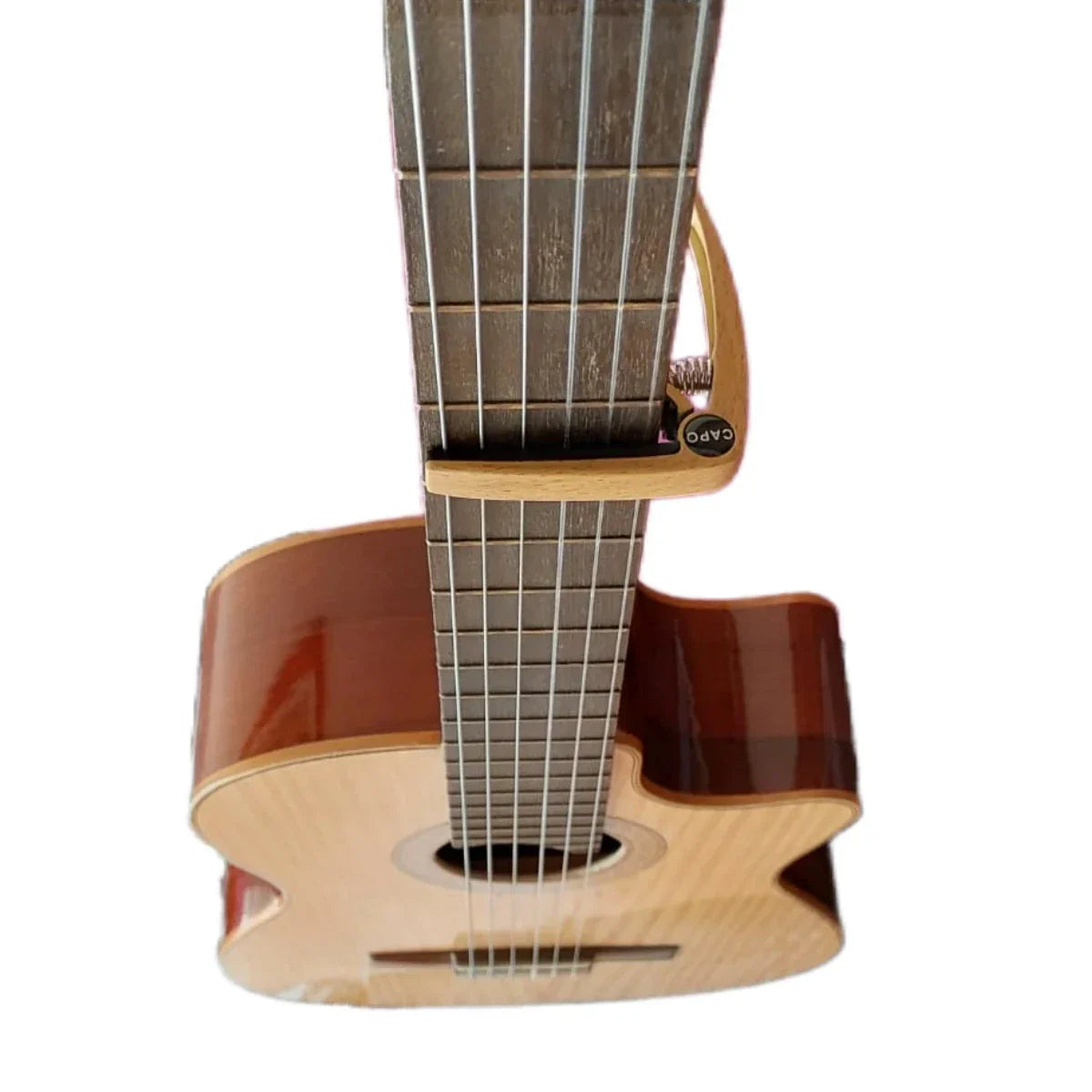 A light wood-finished classical guitar with six strings paired with a guitar capo metal made of zinc alloy construction