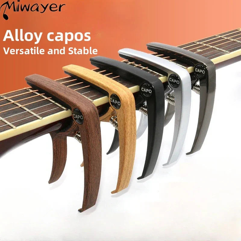 A set of guitar capo metal clamps in wood and black silver zinc alloy construction with spring loaded guitar tuner clamp mechanism