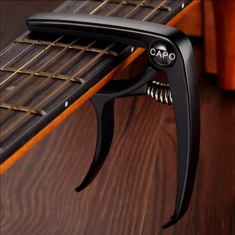 Black metal guitar capo with spring mechanism and capo engraved on circular button for acoustic electric musical use
