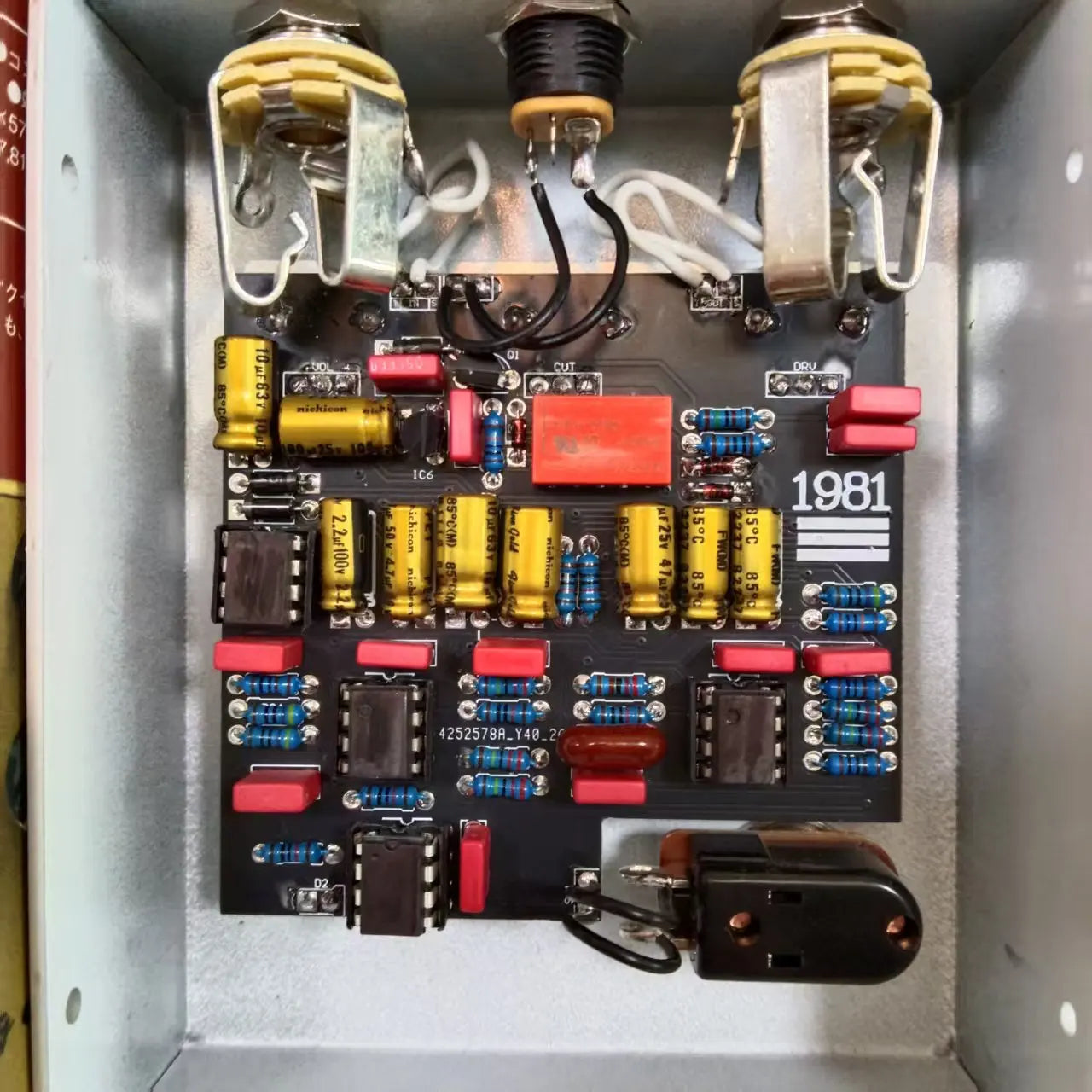 Black circuit board with yellow capacitors red resistors and silver toggle switches in mr xiao guitar effector 1981 with unique mid-frequency overdrive effect