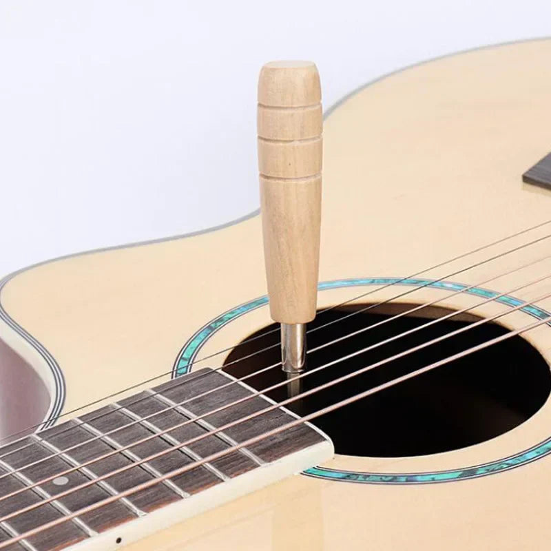 Light-colored wooden guitar wrench hexagon adjusting rod solid handle inserted into soundhole for fingerboard pitch adjustment