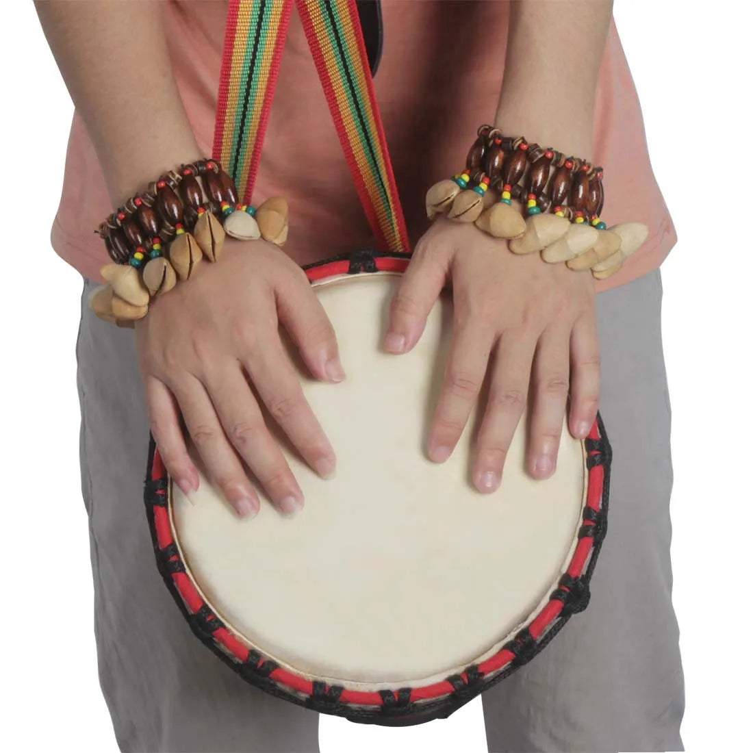 A round beige djembe african drum with handmade nuts shell red and black rim held with beaded bracelet hands
