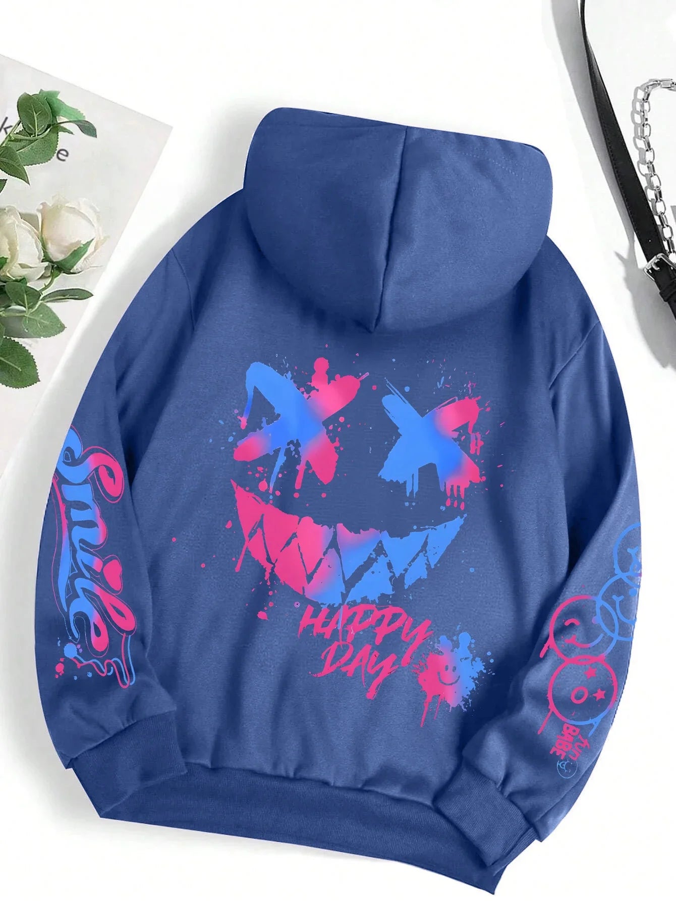 Back of a blue hoodie street hip featuring a vibrant pink and blue happy day graffiti smiley face and matching sleeve graphics