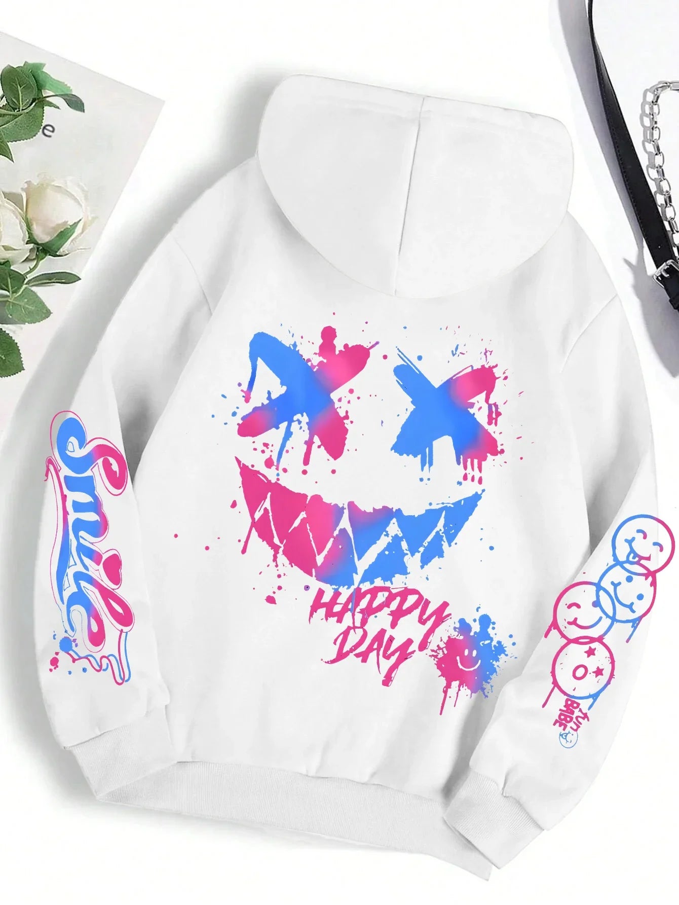 White hoodie featuring happy day graffiti vibrant blue and pink splatter smiley face with colorful sleeve graphics in hoodie street hip style