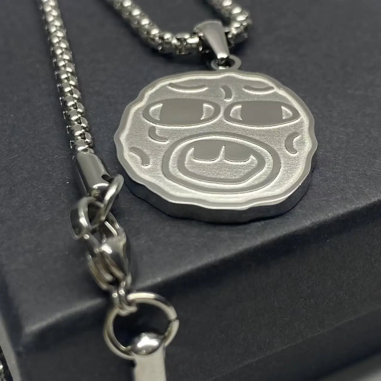 Silver metallic stainless steel hip hop necklace with embossed circular face wearing sunglasses for rapper fan gift