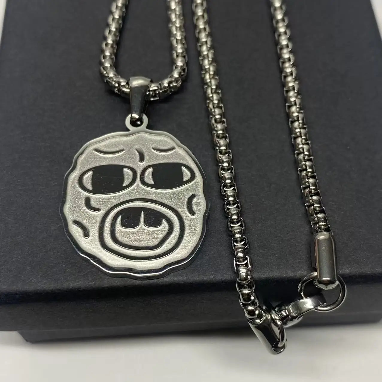 Silver metallic pendant hip hop necklace with round textured face and black inlaid eyes, perfect rapper fan gift accessory