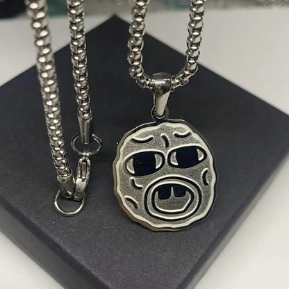 Silver-toned stainless steel hip hop necklace with circular textured face and black inlaid eyes, ideal rapper fan gift