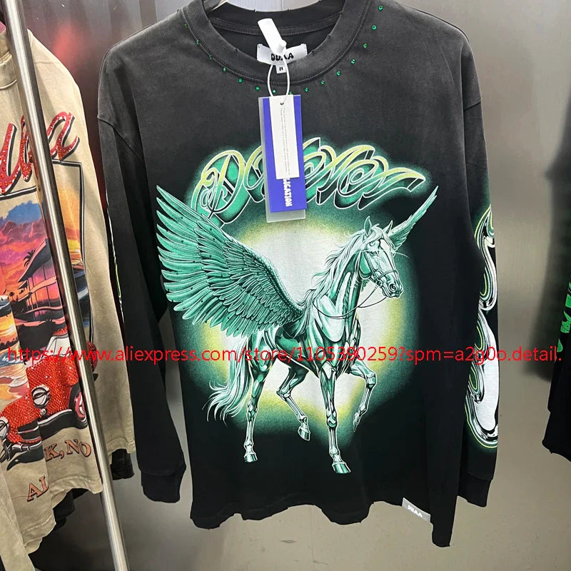 Black long-sleeved tee featuring a vibrant green winged unicorn graphic with neon accents and stylized dolly lettering