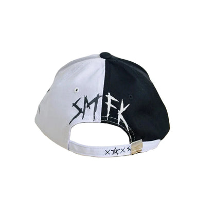 Black and white baseball cap with split graffiti color-block pattern and bold smtfk lettering, a fashionable streetwear accessory
