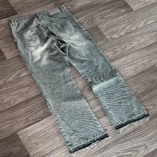 Distressed gray denim jeans with faded wash frayed hems and white hip hop dollar embroidery streetwear unisex back pocket view