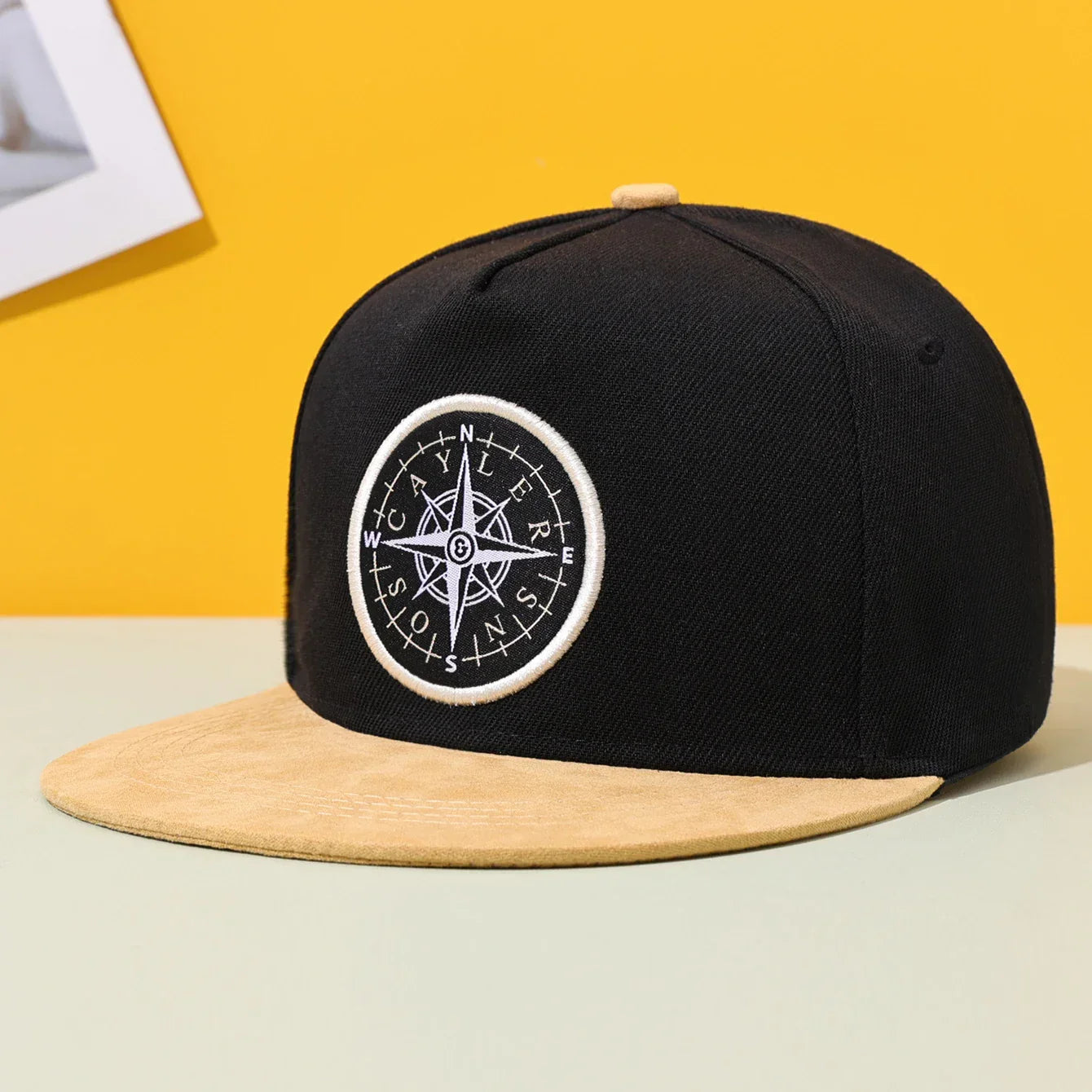 Black hip hop fashion flat brimmed hat with tan suede brim and white compass rose patch for outdoor shading