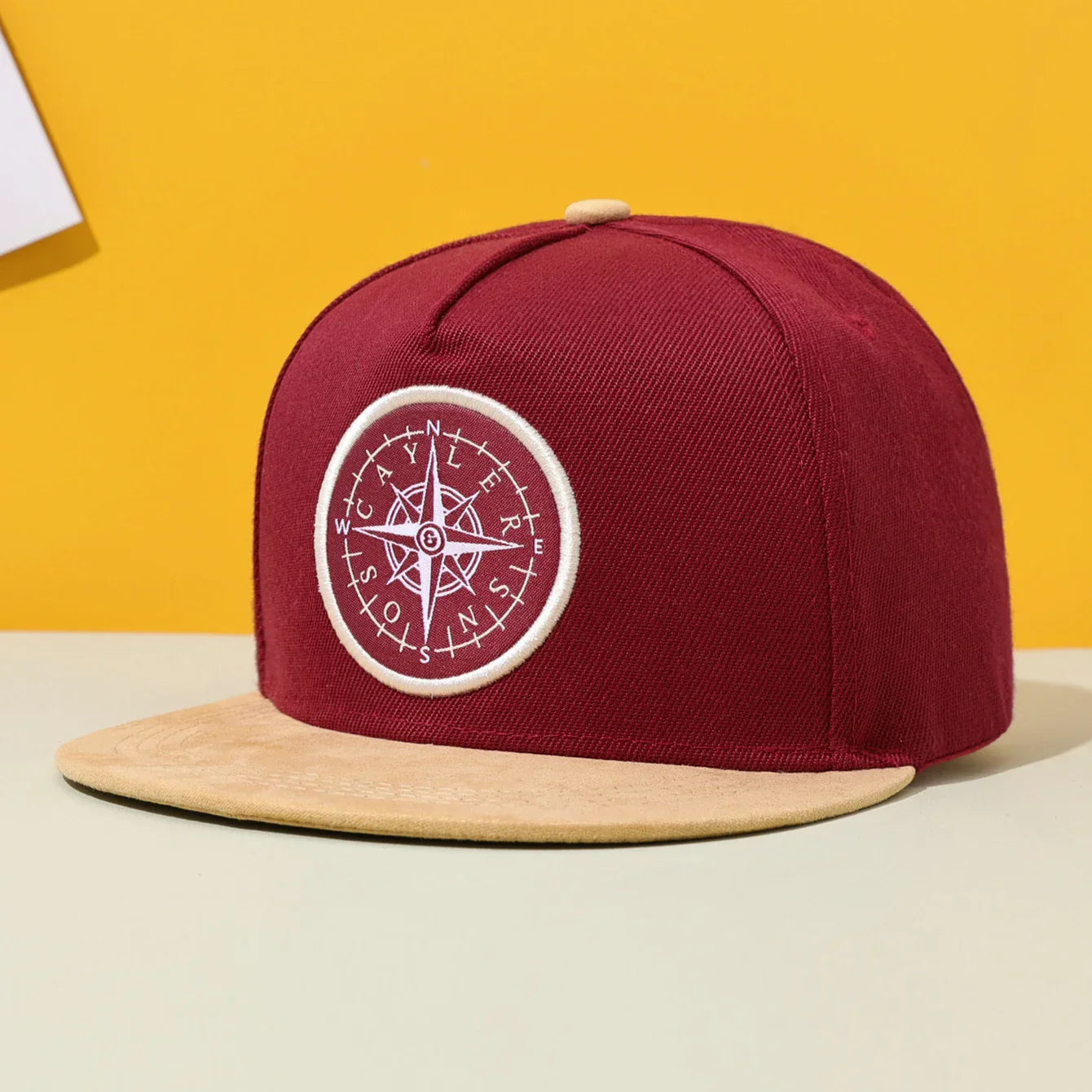 Maroon flat brimmed hat with tan brim and white compass embroidery for hip hop fashion and american street hip style