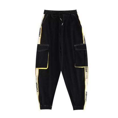 Black cargo pants with bold yellow and white side stripes, large patch pockets, and drawstring waistband for hip hop girls joggers kids streetwear