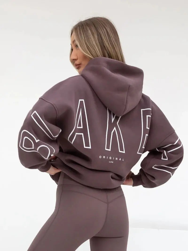 A mauve oversized hoodie men y2k style with bold white outlined letter print on back and sleeves in retro gothic punk design