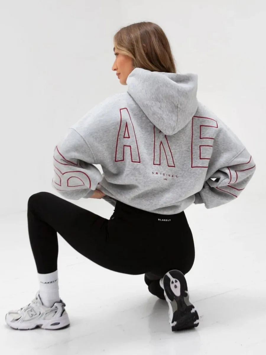Back side of gray oversized hoodie men y2k with bold red outlined lettering and sleeve designs inspired by harajuku high street retro gothic punk