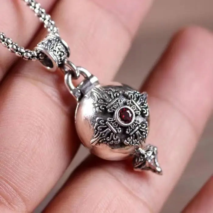 Silver ornate money bag necklace with intricate filigree and a central red gemstone featuring shiny cubic zirconia