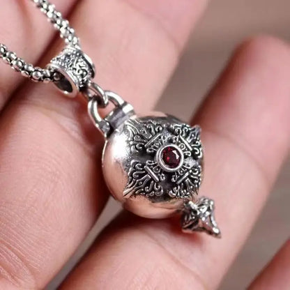 Silver ornate money bag necklace with intricate filigree and a central red gemstone featuring shiny cubic zirconia