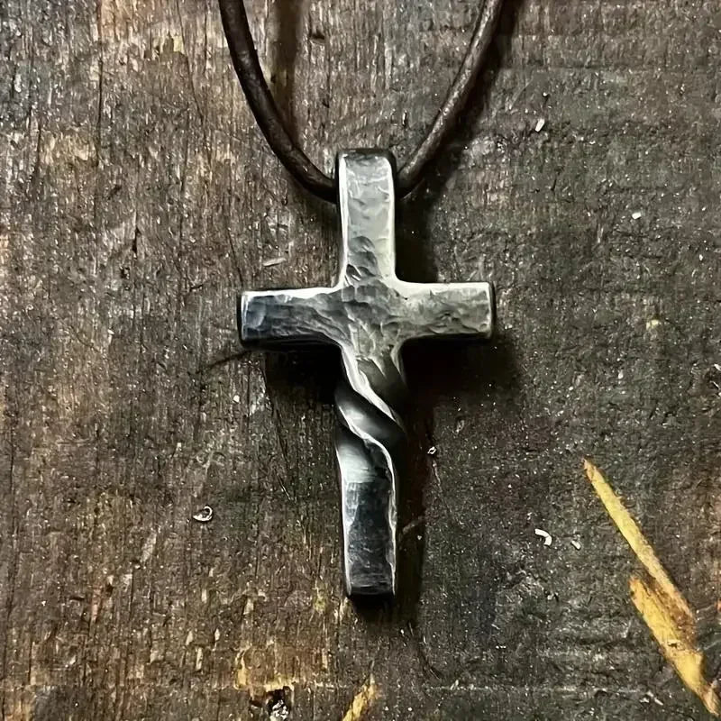 Hand-forged silver cross pendant with twisted design on dark leather cord paired with shiny cubic zirconia money bag necklace