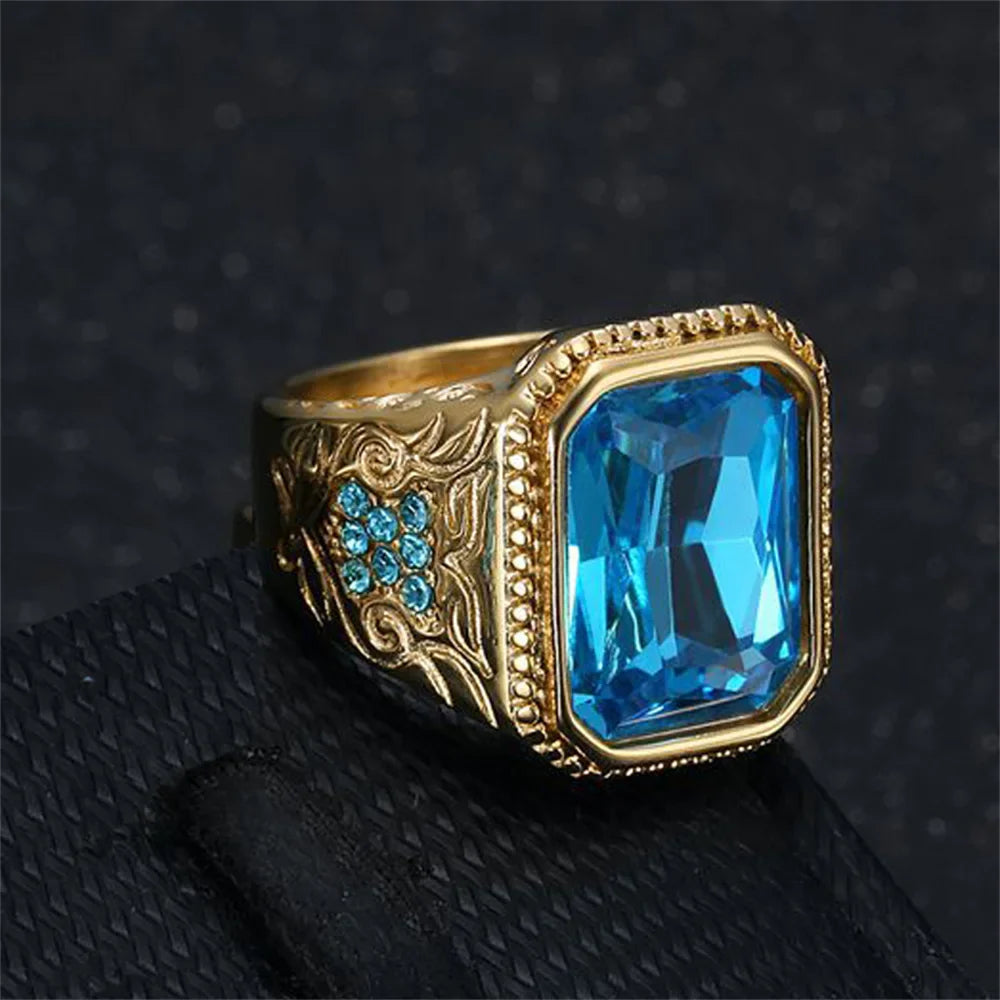 Gold-toned hip hop ring with geometric design featuring a rectangular blue cubic zirconia centerpiece and filigree details