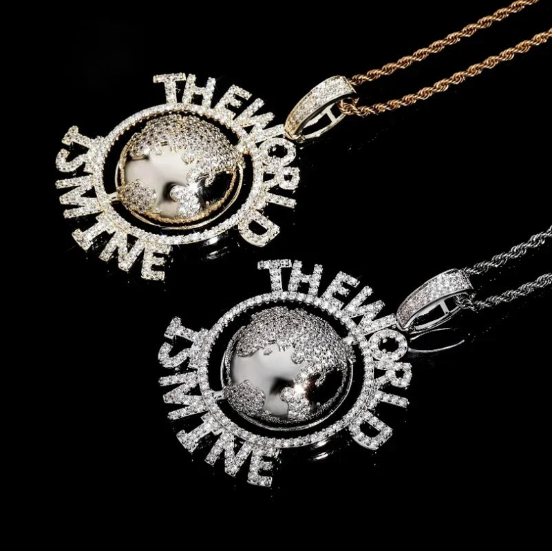 Two diamond-encrusted world globe pendants on chains featuring hip hop letter design and tennis chain fashion style