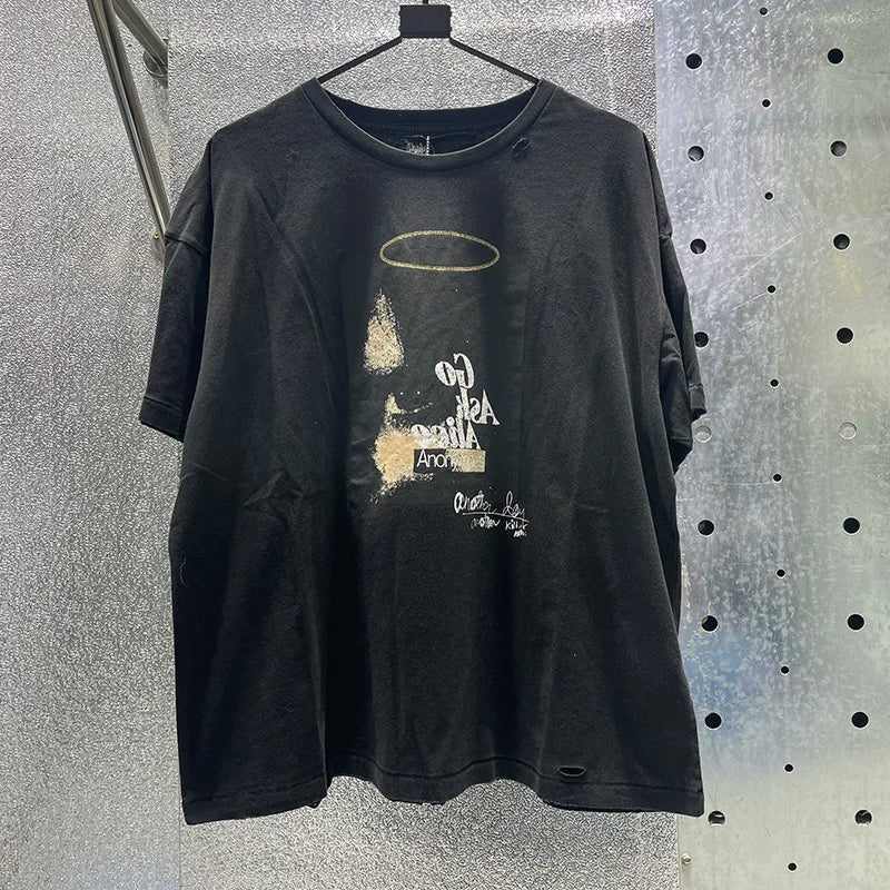 Black distressed cotton graphic tee with hip hop letters, faded gold halo, white text, damaged hole paly design, rhinestone box graphics