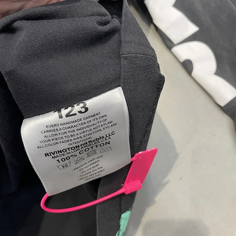 Black cotton garment tag with white label and pink fastener on hip hop letters logo cotton oversized vintage t shirt