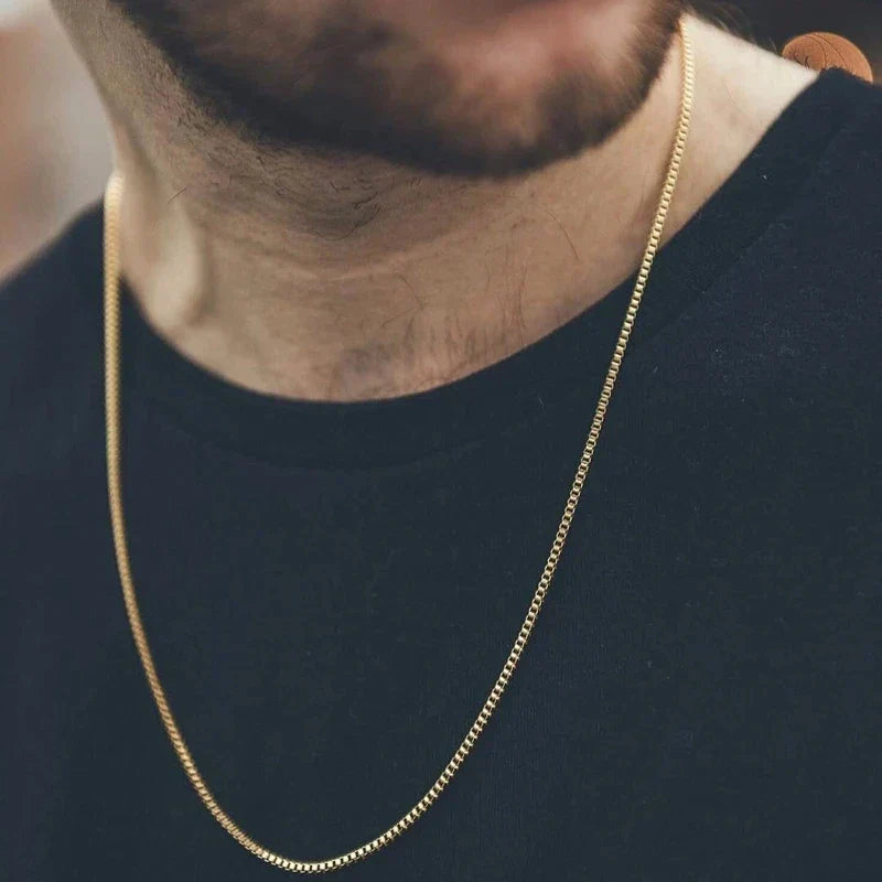 A sleek gold color stainless steel necklace 3mm square pearl chain hip hop necklace worn with a black shirt
