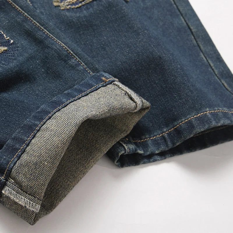 Dark blue denim shorts with rolled cuffs and subtle distressing in retro american streetwear rock motorcycle denim style