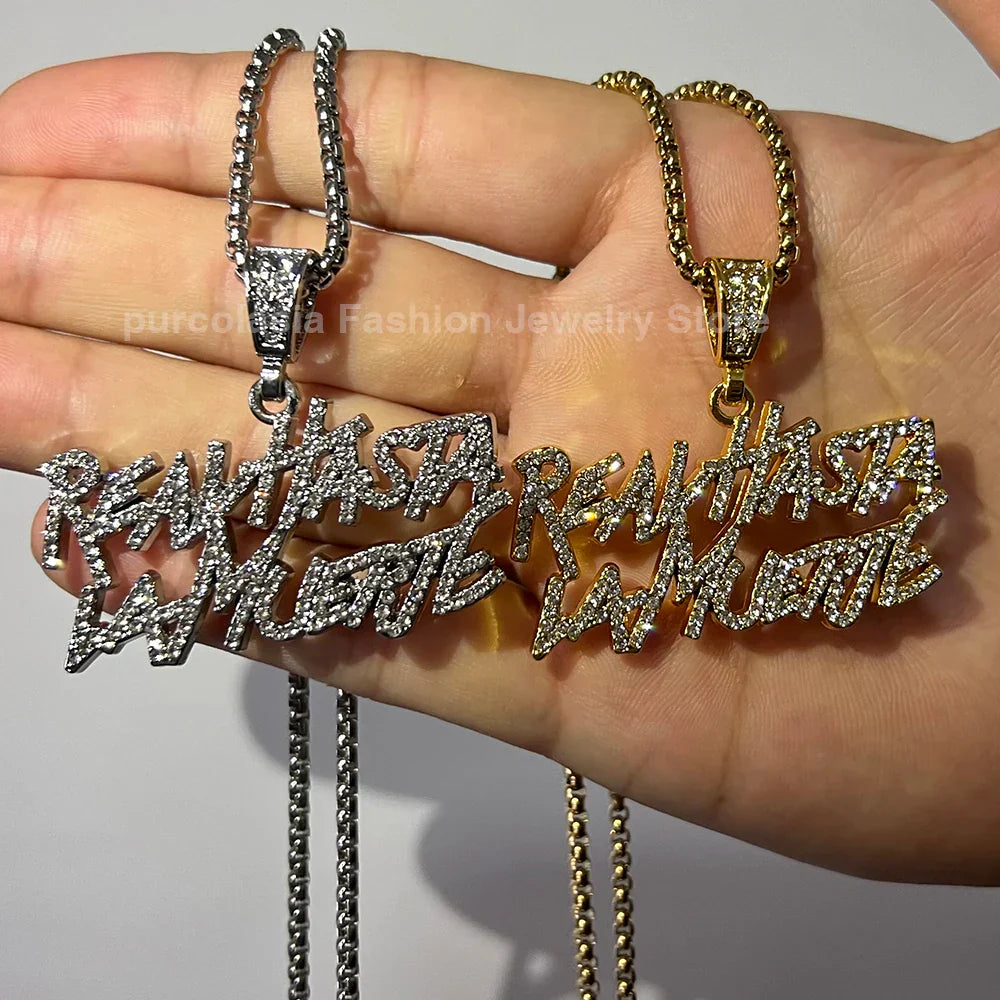 Two rhinestone-encrusted realhasta lamuerte letter bling pendant necklaces in silver and gold tone with bling chain iced