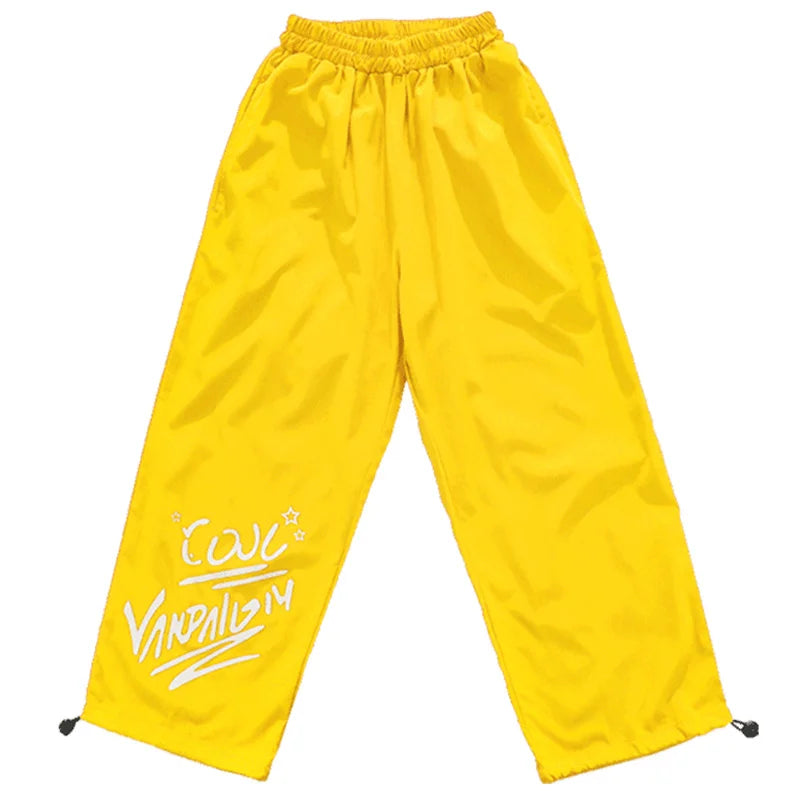 Bright yellow satin hip hop pants with white vandalism logo in a kids clothing set for streetwear performance