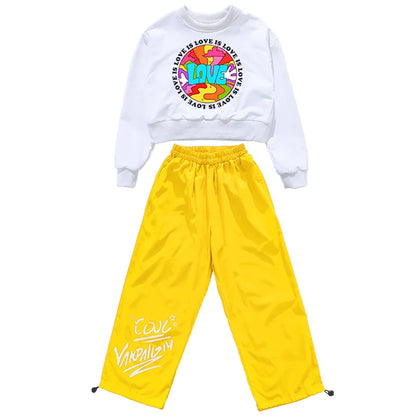 White cropped sweatshirt with colorful love graphic and yellow satin pants with white graffiti lettering hip hop clothing set