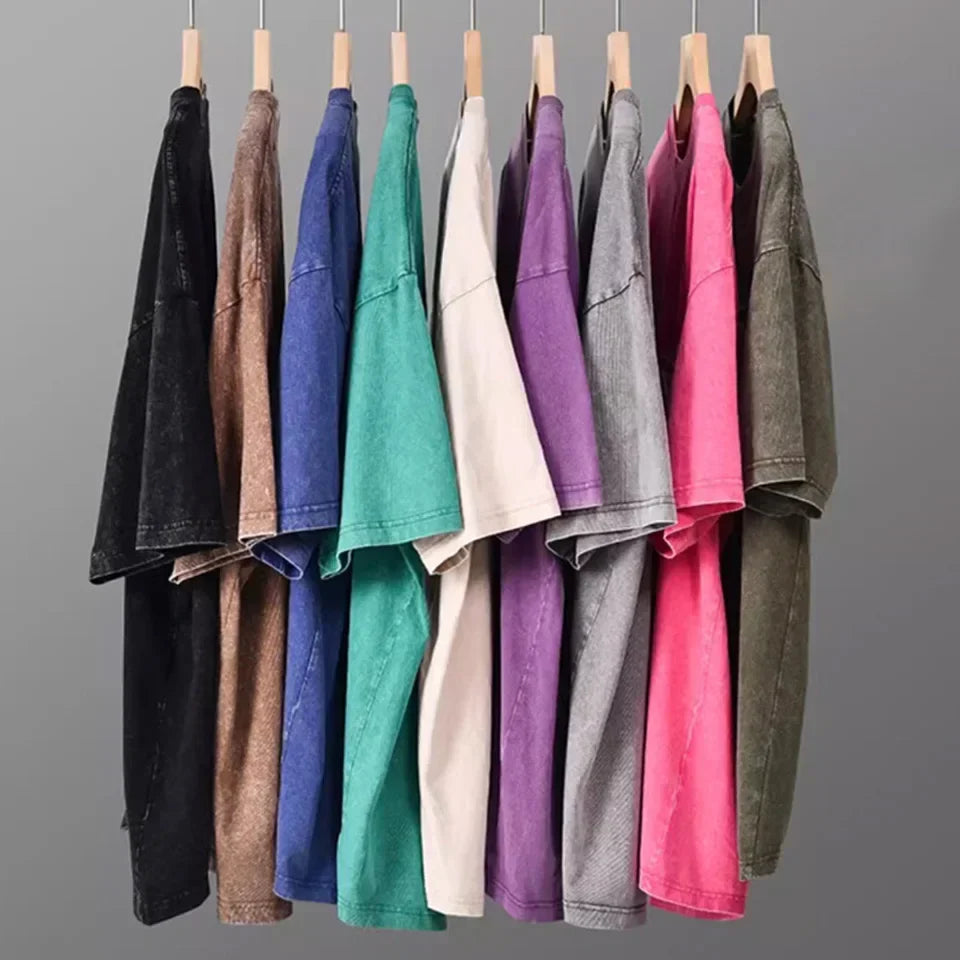 A row of harajuku multicolors oversized distressed denim unisex summer retro t shirts on wooden hangers for men fashion cotton