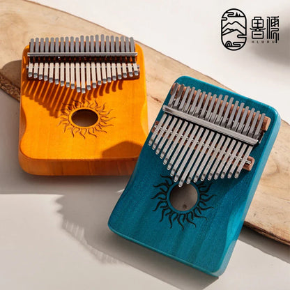 Two colorful wooden kalimba finger pianos in orange and teal with sun carvings for beginner music lovers