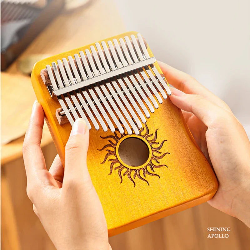 A warm yellow wooden kalimba finger piano with sun-engraved sound hole and silver metal tines musical instrument mbira