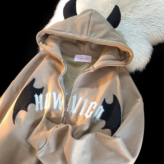 Beige zip-up hoodie with black devil horns embroidered bat wings and white gothic lettering for dark vintage streetwear