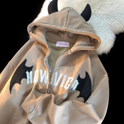 Beige zip-up hoodie with black devil horns and bat appliqués featuring white howlie graphic in vintage harajuku hoody style