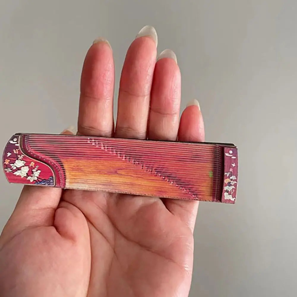 A compact handheld wooden zither with red orange gradient and white floral pattern for dollhouse musical instruments courtesan pattern