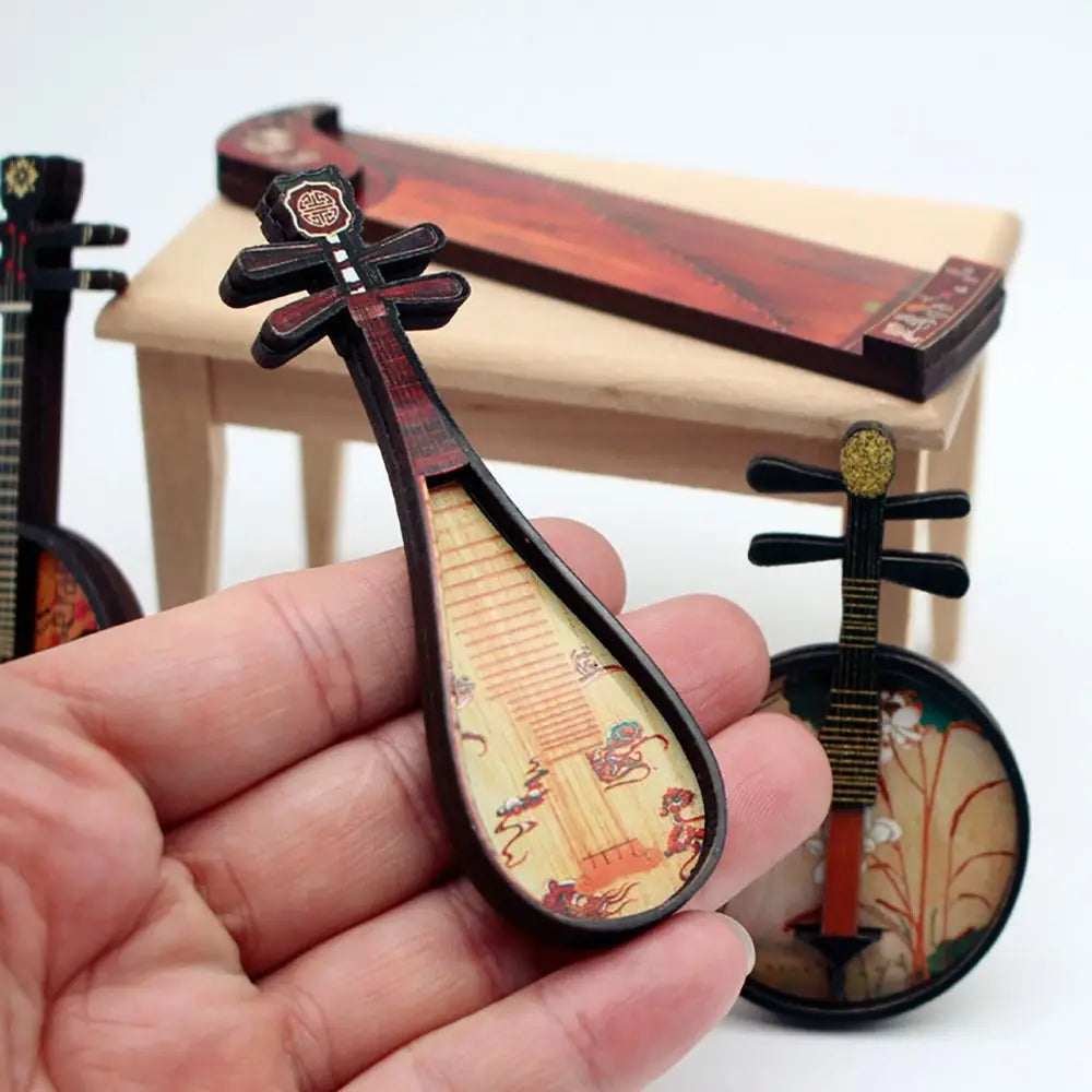 A hand holds a miniature dollhouse musical instrument with a dark wood frame and chinese classical instrument design