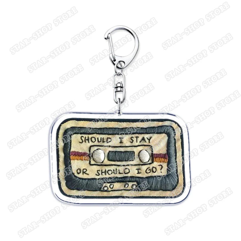 A beige fabric rectangular embroidered cassette tape keychain with should i stay or should i go text for byers eleven mike fans gifts