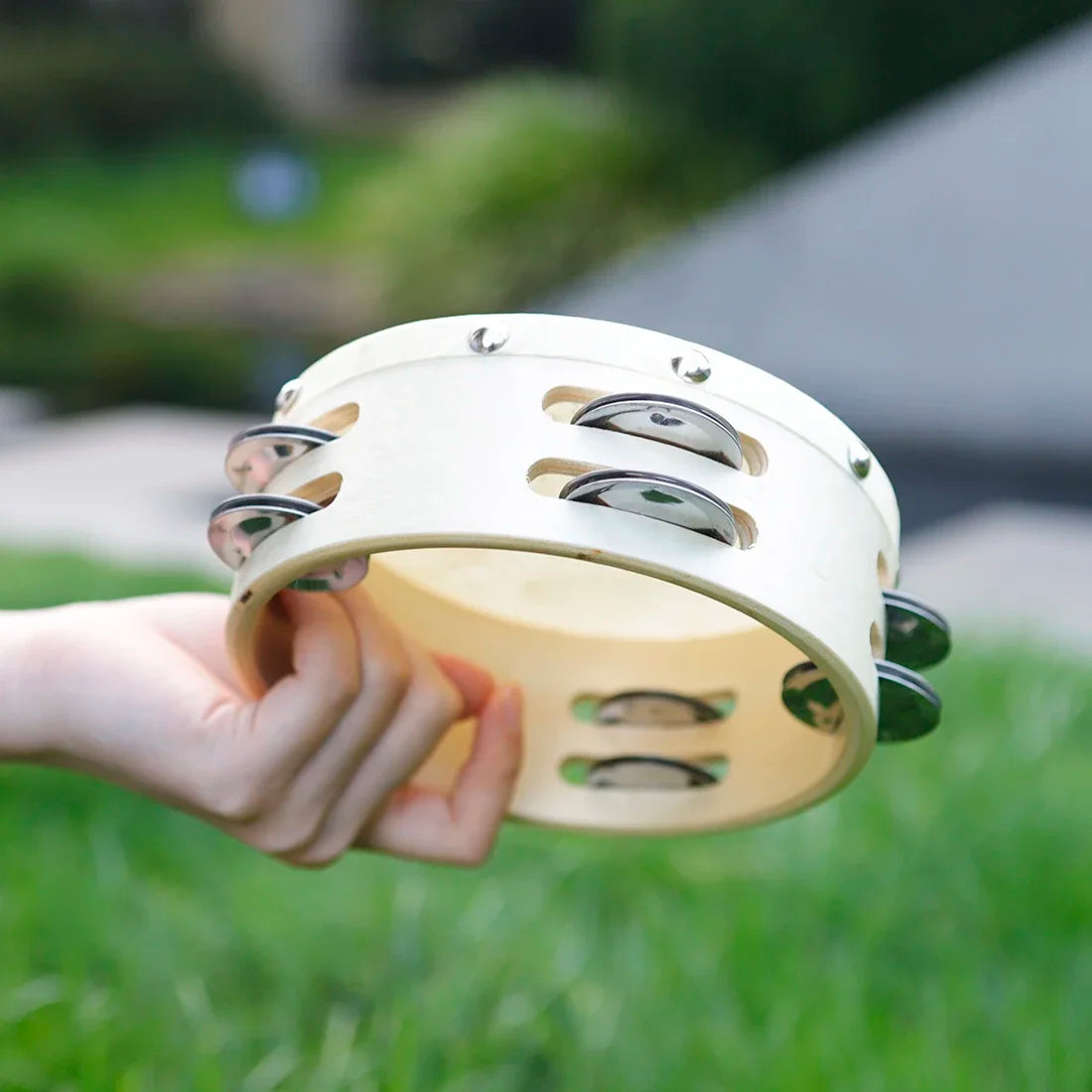 A cream-colored irin orff 6 inch tambourine sheepskin with silver jingles for children enlightenment music education