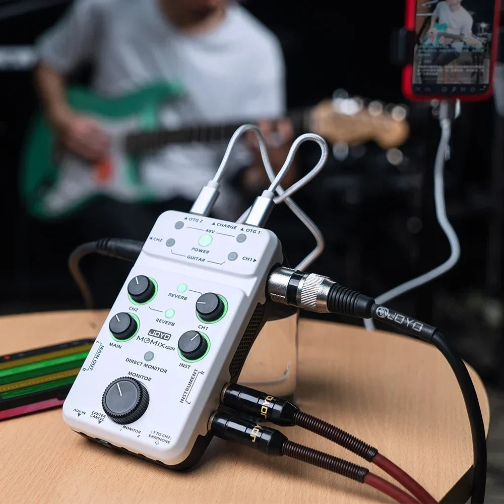 White Joyo momix pro audio mixer with green-lit knobs and black cables for recording and live streaming use