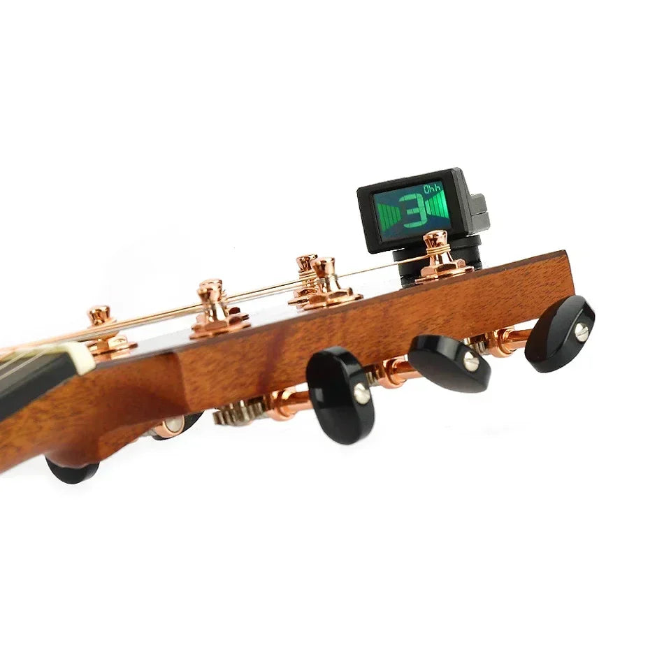 Black digital mini guitar tuner with green led display clipped on wooden electric acoustic classic guitar headstock