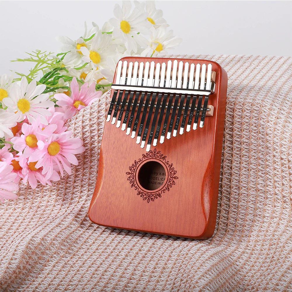 A polished reddish-brown kalimba finger piano with 21 black and silver keys and ornate sound hole musical instrument mbira